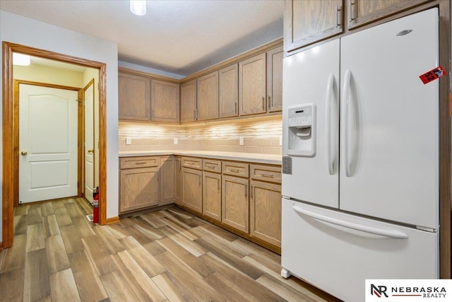 650 Heatherwood Dr, Fremont, NE 68025 - kitchen with white fridge with ice dispenser, light wood-style floors, tasteful backsplash, and light countertops