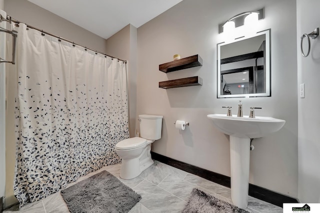 17380 S 77th Pt, Hickman, NE 68372 - bathroom with baseboards, toilet, a shower with curtain, marble look tile flooring, and a sink