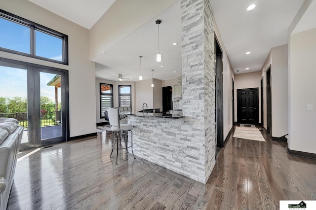 17380 S 77th Pt, Hickman, NE 68372 - kitchen featuring dark wood finished floors, open floor plan, a breakfast bar, ceiling fan, and white cabinets