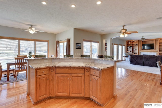 4804 Fountain Cir, Papillion, NE 68133 - kitchen featuring ceiling fan, a textured ceiling, light wood-type flooring, a fireplace, and open floor plan