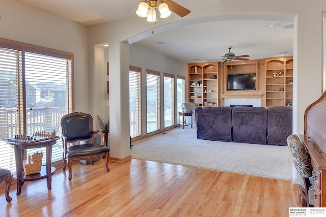 4804 Fountain Cir, Papillion, NE 68133 - living area with a ceiling fan, a fireplace, arched walkways, and light wood-style floors