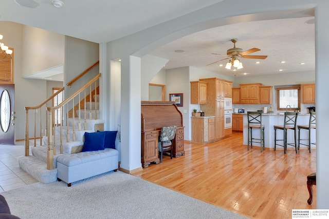 4804 Fountain Cir, Papillion, NE 68133 - living area featuring ceiling fan, stairway, arched walkways, baseboards, and light wood-style floors