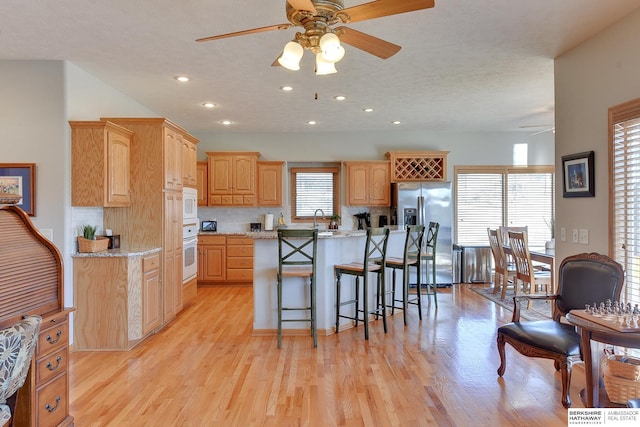 4804 Fountain Cir, Papillion, NE 68133 - kitchen featuring ceiling fan, white appliances, a center island, a kitchen bar, and light wood finished floors
