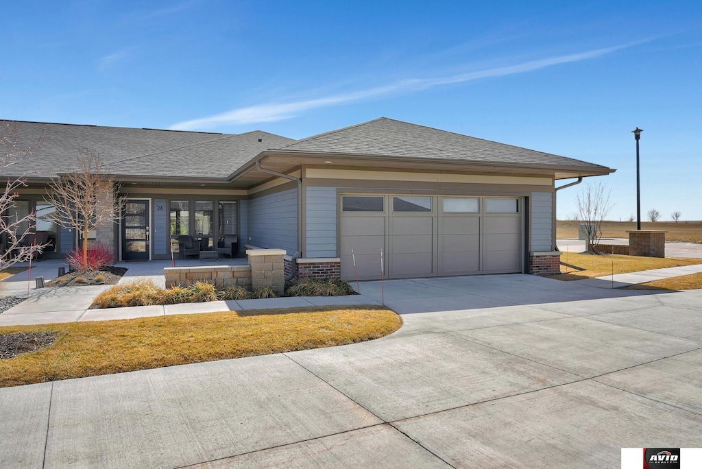 6630 Juliet Ct Unit 2A, Lincoln, NE 68521 - view of front of home featuring driveway, brick siding, a garage, and roof with shingles