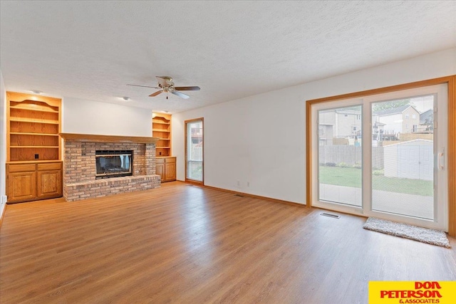 3412 Rahn Blvd, Bellevue, NE 68123 - unfurnished living room with a textured ceiling, light wood finished floors, ceiling fan, built in shelves, and a brick fireplace