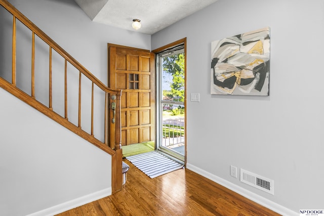 8207 Decatur St, Omaha, NE 68114 - foyer entrance featuring stairway, baseboards, wood finished floors, and a textured ceiling