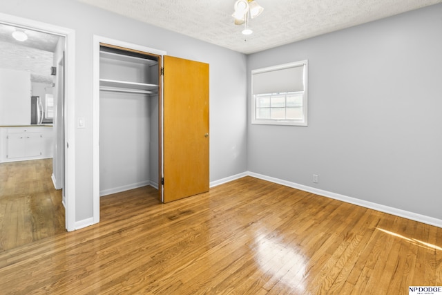 8207 Decatur St, Omaha, NE 68114 - unfurnished bedroom featuring a textured ceiling, light wood-style floors, baseboards, a closet, and freestanding refrigerator