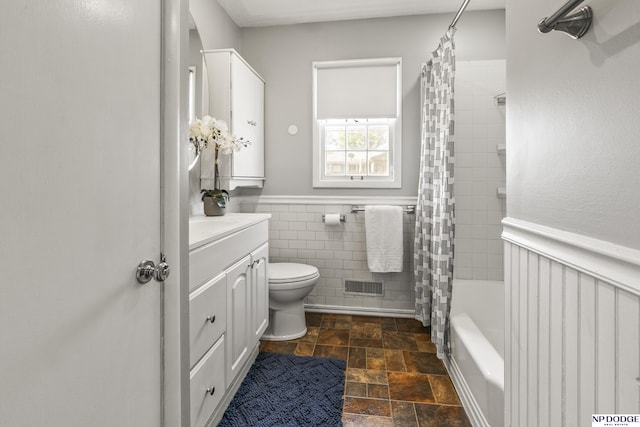 8207 Decatur St, Omaha, NE 68114 - full bath with vanity, stone finish floors, a wainscoted wall, toilet, and shower / bath combination with curtain