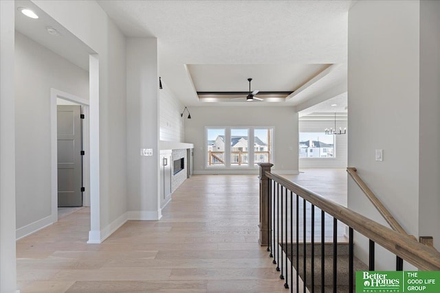 5729 N 196th St, Elkhorn, NE 68022 - corridor with light wood-style floors, a raised ceiling, an upstairs landing, baseboards, and a chandelier