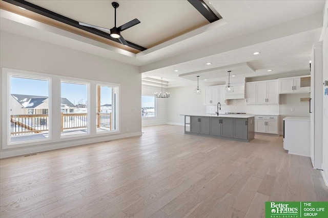5729 N 196th St, Elkhorn, NE 68022 - unfurnished living room featuring a tray ceiling, a ceiling fan, light wood finished floors, a chandelier, and recessed lighting