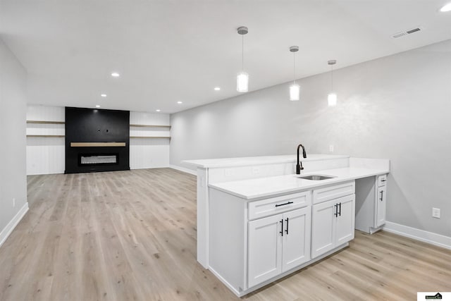 7949 Ponce Dr, Lincoln, NE 68516 - kitchen featuring a sink, light wood finished floors, white cabinets, baseboards, and hanging light fixtures