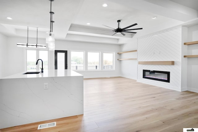 7949 Ponce Dr, Lincoln, NE 68516 - unfurnished living room featuring a sink, a tray ceiling, light wood finished floors, baseboards, and ceiling fan