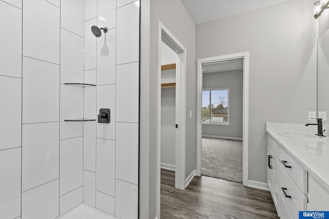 5948 Loxton St, Lincoln, NE 68526 - bathroom featuring a tile shower, baseboards, wood finished floors, and vanity
