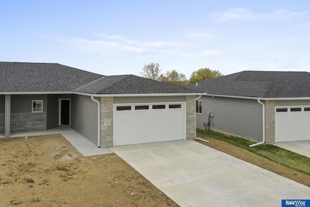 5956 Loxton St, Lincoln, NE 68526 - view of front of home featuring a garage, roof with shingles, stone siding, and concrete driveway