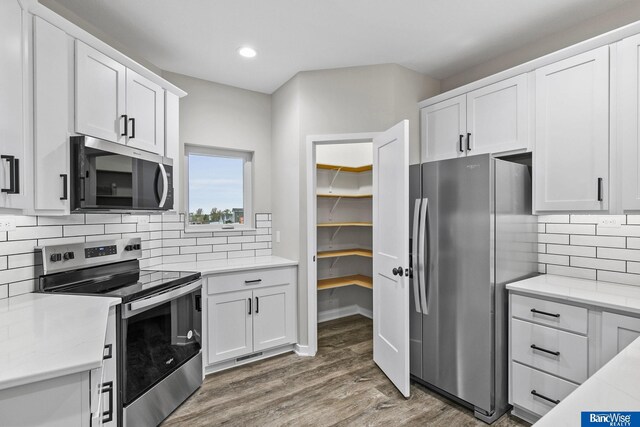 5956 Loxton St, Lincoln, NE 68526 - kitchen featuring appliances with stainless steel finishes, recessed lighting, wood finished floors, white cabinets, and backsplash