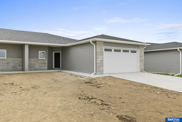 5956 Loxton St, Lincoln, NE 68526 - view of front facade featuring stone siding, an attached garage, driveway, and roof with shingles