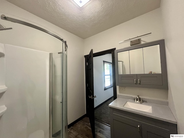 231 N Government St, Valentine, NE 69201 - full bathroom featuring wood finished floors, a shower stall, vanity, a textured ceiling, and baseboards