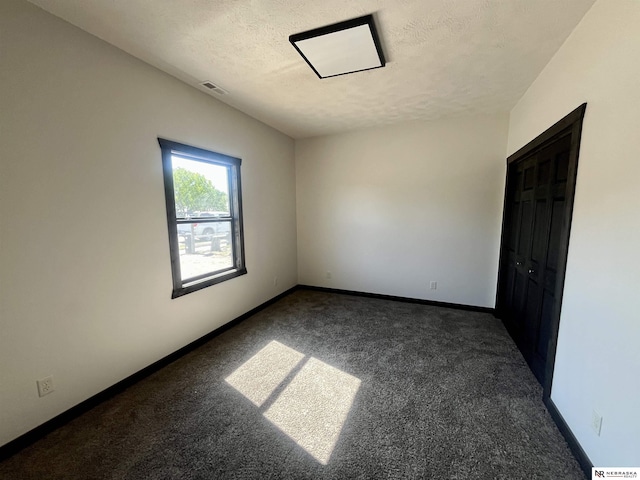 231 N Government St, Valentine, NE 69201 - empty room with dark carpet, a textured ceiling, and baseboards