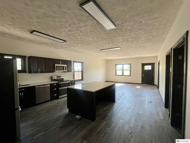 231 N Government St, Valentine, NE 69201 - kitchen featuring appliances with stainless steel finishes, dark cabinets, dark wood-style floors, a kitchen island, and light countertops