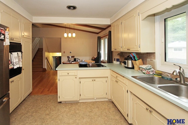 6810 S St S, Lincoln, NE 68506 - kitchen with a peninsula, black electric cooktop, a sink, light countertops, and decorative backsplash