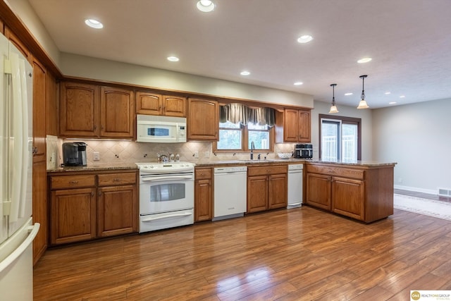 10919 N 69th St, Omaha, NE 68152 - kitchen featuring white appliances, brown cabinetry, a sink, a peninsula, and dark wood-type flooring