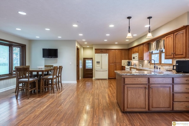 10919 N 69th St, Omaha, NE 68152 - kitchen featuring white appliances, a sink, brown cabinetry, light stone counters, and baseboards