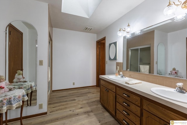 10919 N 69th St, Omaha, NE 68152 - bathroom featuring double vanity, wood finished floors, a skylight, decorative backsplash, and baseboards