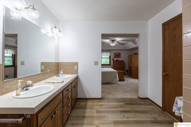 10919 N 69th St, Omaha, NE 68152 - bathroom with double vanity, wood finished floors, tasteful backsplash, ensuite bathroom, and a ceiling fan
