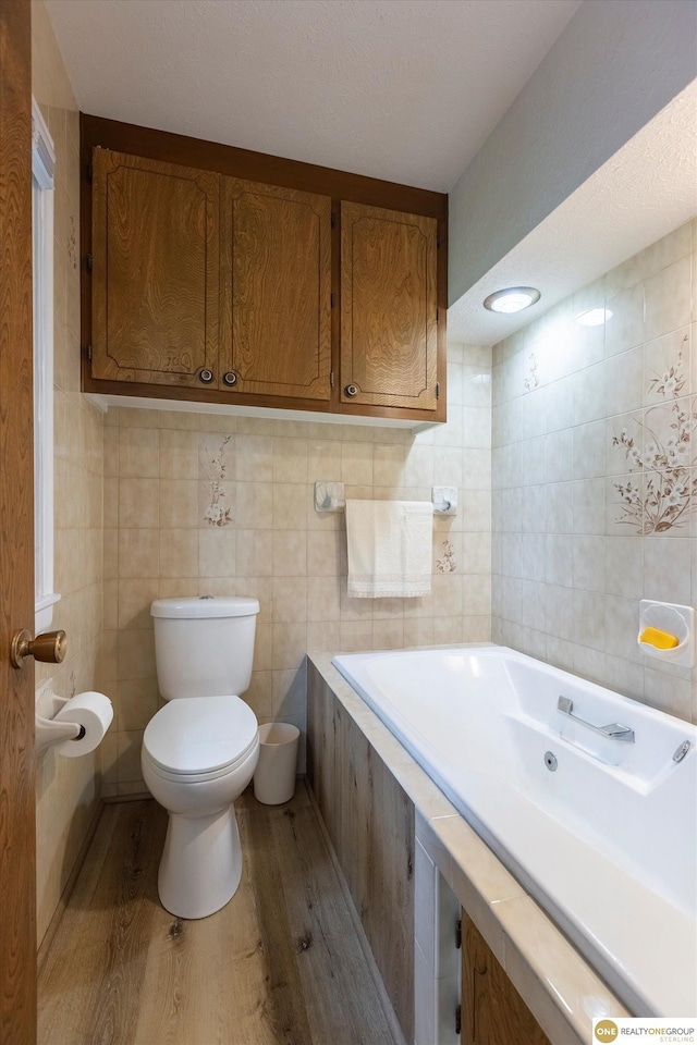 10919 N 69th St, Omaha, NE 68152 - bathroom featuring wood finished floors, tile walls, toilet, and a tub