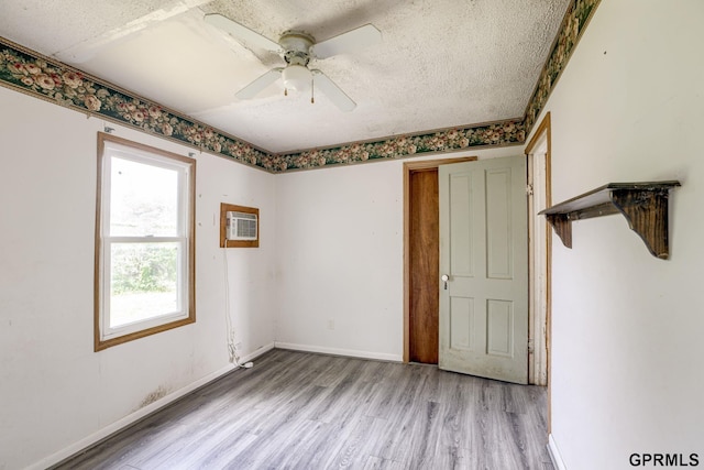 165 Monroe St, Bennet, NE 68317 - unfurnished bedroom with light wood finished floors, a textured ceiling, baseboards, an AC wall unit, and ceiling fan