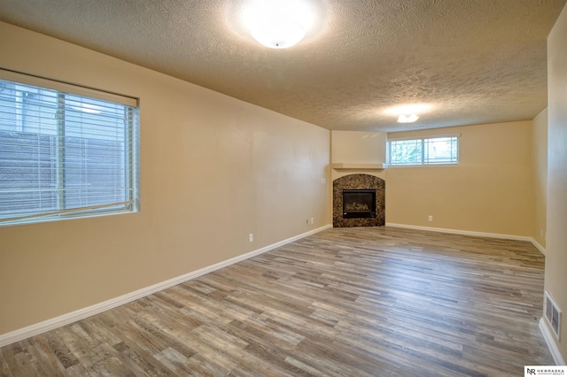 5306 S 195th St, Omaha, NE 68135 - unfurnished living room featuring a textured ceiling, wood finished floors, a glass covered fireplace, and baseboards