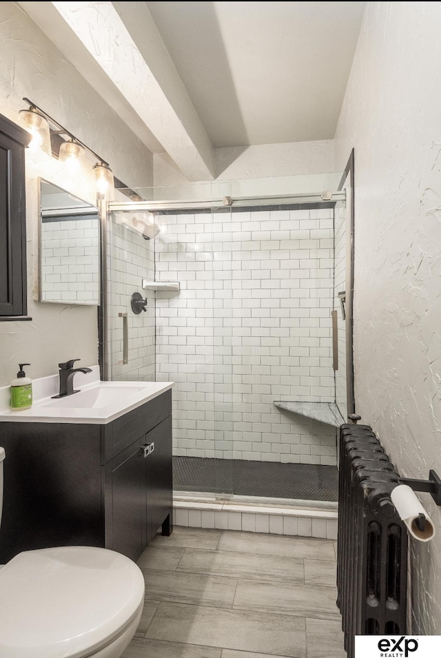 131 S 39th St Unit 6, Omaha, NE 68131 - bathroom featuring a stall shower, radiator heating unit, vanity, toilet, and wood finished floors