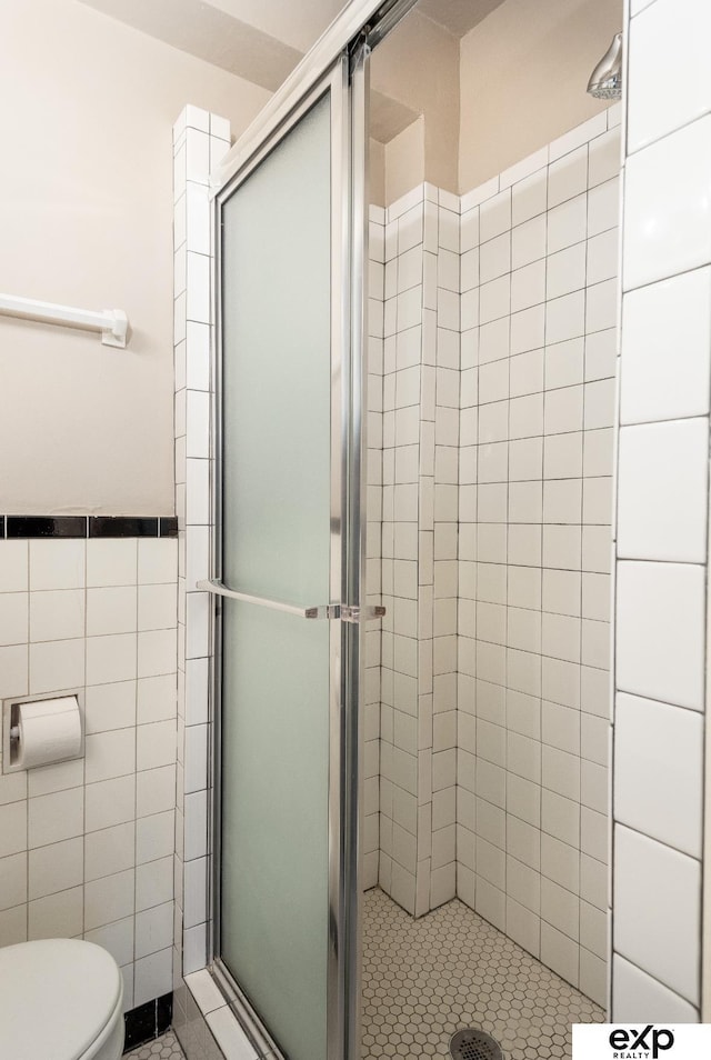 131 S 39th St Unit 6, Omaha, NE 68131 - bathroom featuring tile walls, a stall shower, toilet, tile patterned floors, and a wainscoted wall