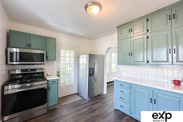 2626 N 67th St, Omaha, NE 68104 - kitchen featuring stainless steel appliances, arched walkways, light countertops, tasteful backsplash, and dark wood-type flooring
