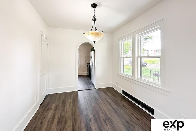 2626 N 67th St, Omaha, NE 68104 - unfurnished dining area featuring dark wood-style flooring, arched walkways, and baseboards