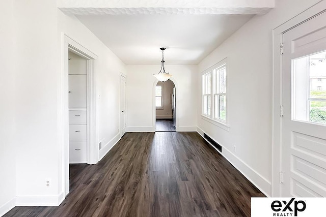 2626 N 67th St, Omaha, NE 68104 - unfurnished dining area with arched walkways, dark wood finished floors, and baseboards