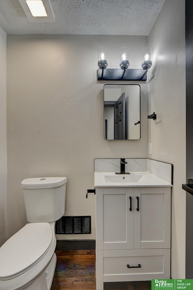 11680 Meredith Ave, Omaha, NE 68164 - half bathroom featuring vanity, a textured ceiling, toilet, and wood finished floors