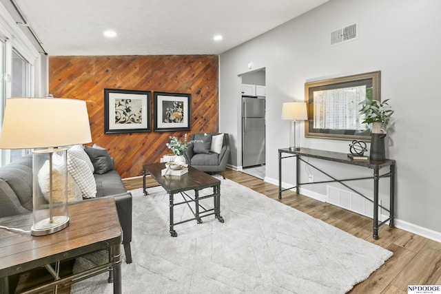 4656 Redick Ave, Omaha, NE 68152 - living room with an accent wall, wood walls, baseboards, recessed lighting, and wood finished floors