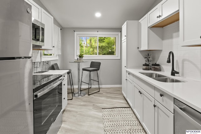 4656 Redick Ave, Omaha, NE 68152 - kitchen with stainless steel appliances, a sink, baseboards, decorative backsplash, and white cabinets