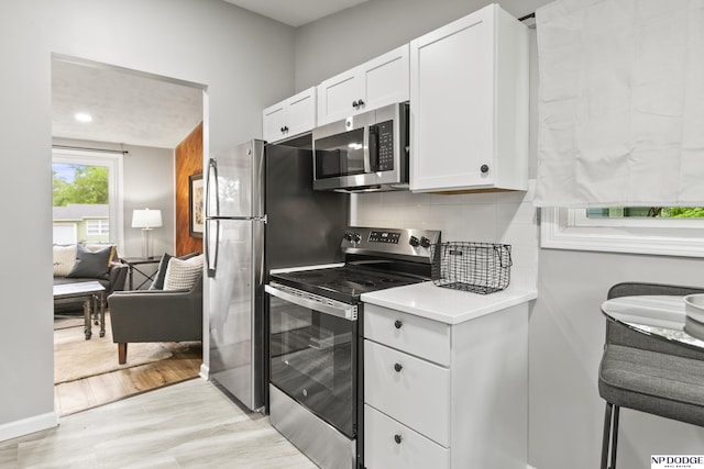 4656 Redick Ave, Omaha, NE 68152 - kitchen featuring stainless steel appliances, white cabinets, tasteful backsplash, light countertops, and light wood finished floors