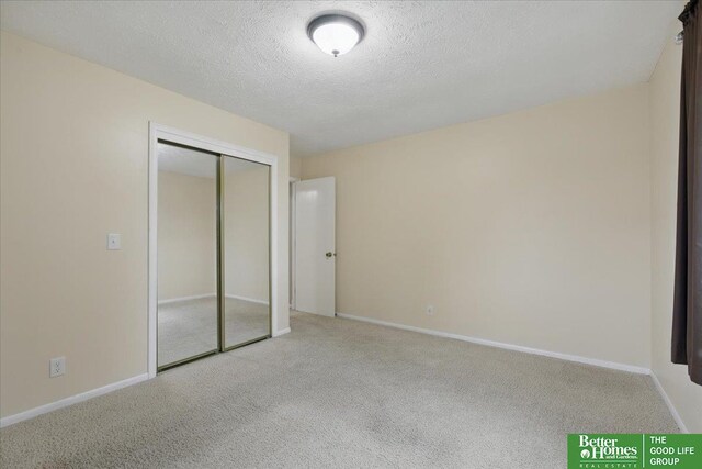 5143 S 126th Plz Unit 22, Omaha, NE 68137 - unfurnished bedroom with carpet flooring, a closet, a textured ceiling, and baseboards