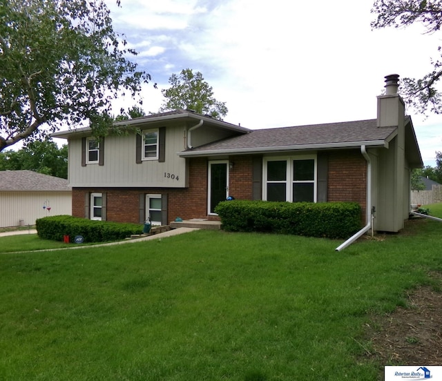 1304 S 4th Ave, Beatrice, NE 68310 - split level home with a chimney, brick siding, and a front yard