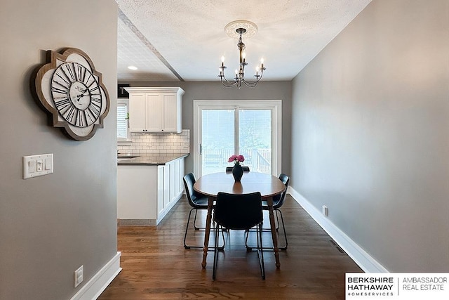 3120 N 205th St, Omaha, NE 68022 - dining space featuring a chandelier, dark wood-type flooring, baseboards, and a textured ceiling