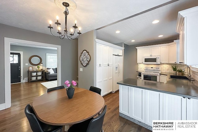 3120 N 205th St, Omaha, NE 68022 - kitchen featuring a sink, white appliances, a chandelier, tasteful backsplash, and dark wood-style flooring