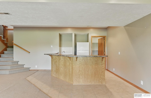 211 Longwood Dr, Papillion, NE 68133 - kitchen featuring freestanding refrigerator, a kitchen bar, light tile patterned floors, a textured ceiling, and baseboards
