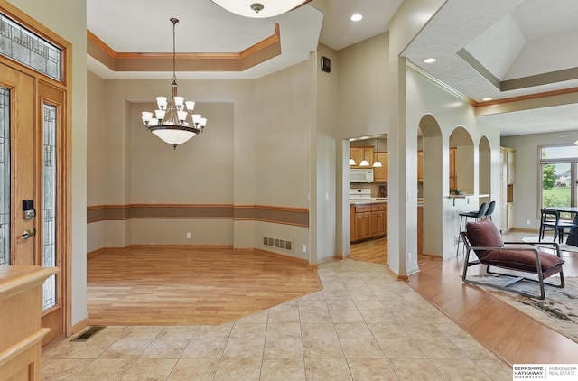 211 Longwood Dr, Papillion, NE 68133 - foyer featuring ornamental molding, a tray ceiling, a chandelier, baseboards, and light wood-style floors