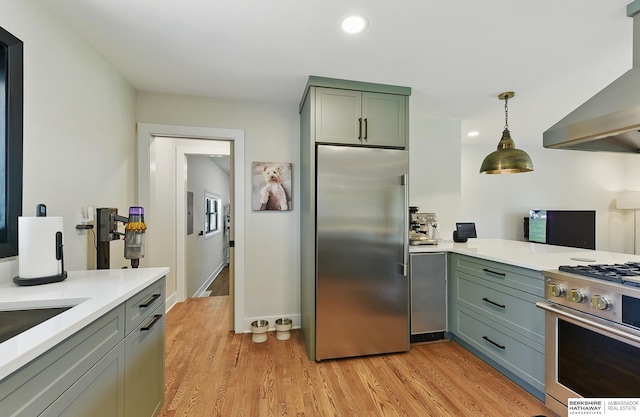 317 N 96th St, Omaha, NE 68114 - kitchen with high end appliances, wall chimney exhaust hood, light countertops, light wood finished floors, and decorative light fixtures