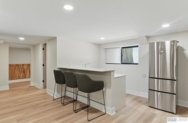 317 N 96th St, Omaha, NE 68114 - kitchen featuring freestanding refrigerator, light wood-style flooring, a breakfast bar, a peninsula, and baseboards
