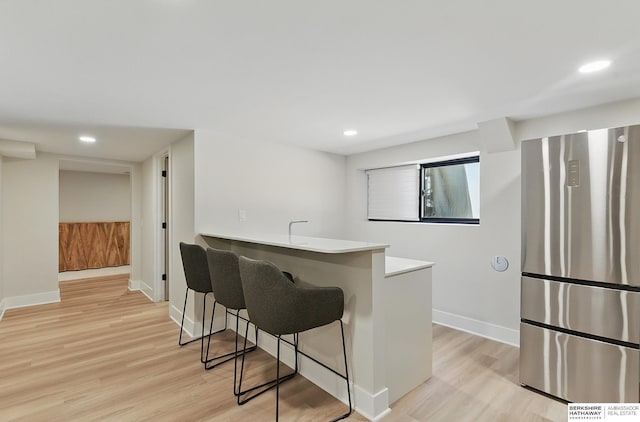 317 N 96th St, Omaha, NE 68114 - kitchen with freestanding refrigerator, a breakfast bar, light wood-style floors, recessed lighting, and baseboards