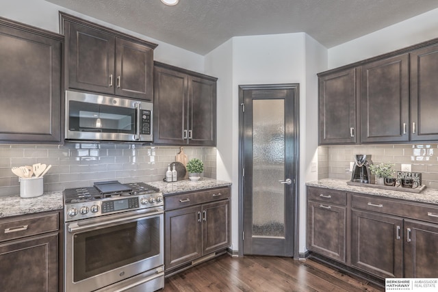 7812 S 196th St, Gretna, NE 68028 - kitchen featuring appliances with stainless steel finishes, dark wood finished floors, dark brown cabinets, light stone countertops, and a textured ceiling